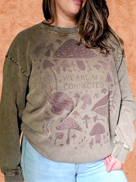 Person wearing a sweatshirt with mushroom design and 'We are all connected' text on an orange background