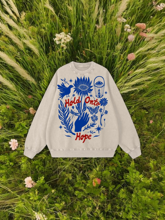 White sweatshirt with blue and red design on grass and flowers