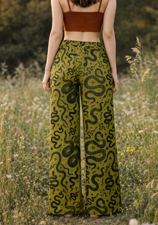 Person wearing green snake print pants and a brown top in a field