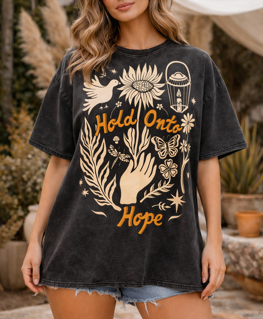 Woman wearing a black t-shirt with a graphic design and text, standing outdoors.