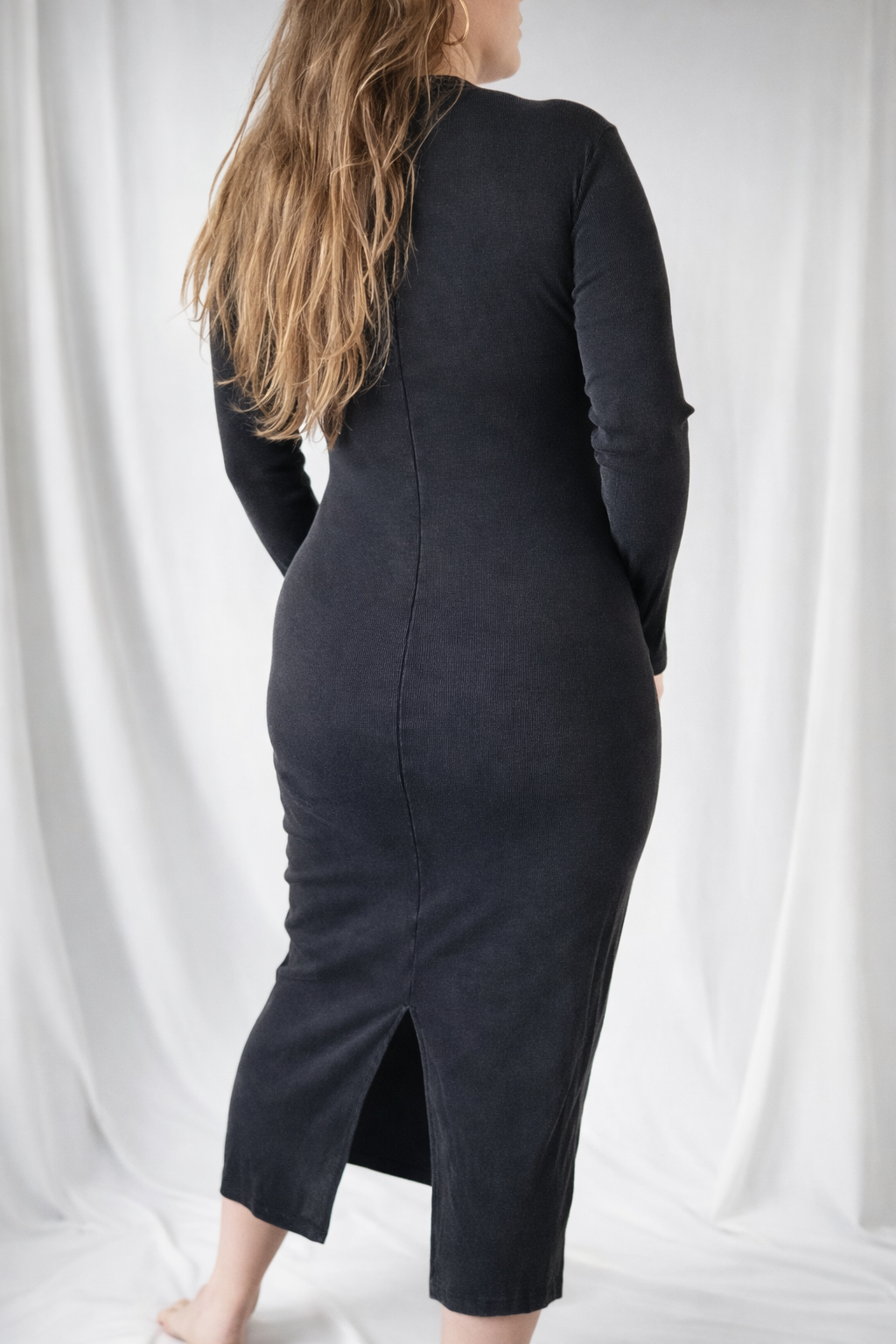 Person wearing a black dress with a slit on a white background