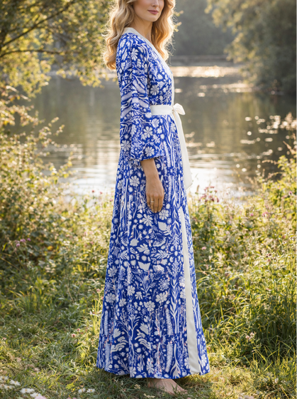 Woman in a blue floral kimono robe  standing by a river with trees in the background