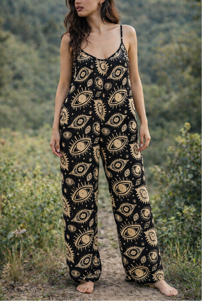 Woman wearing a witchy black and gold patterned jumpsuit standing in a natural setting.