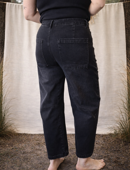 Person wearing dark jeans standing against a neutral background