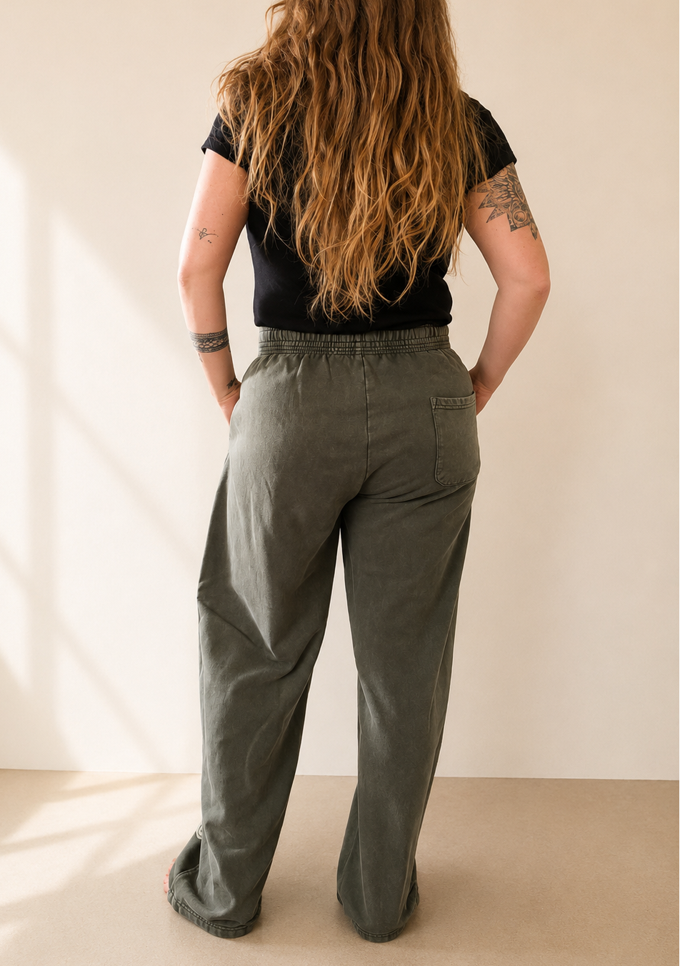 Person wearing green pants and a black top against a plain background