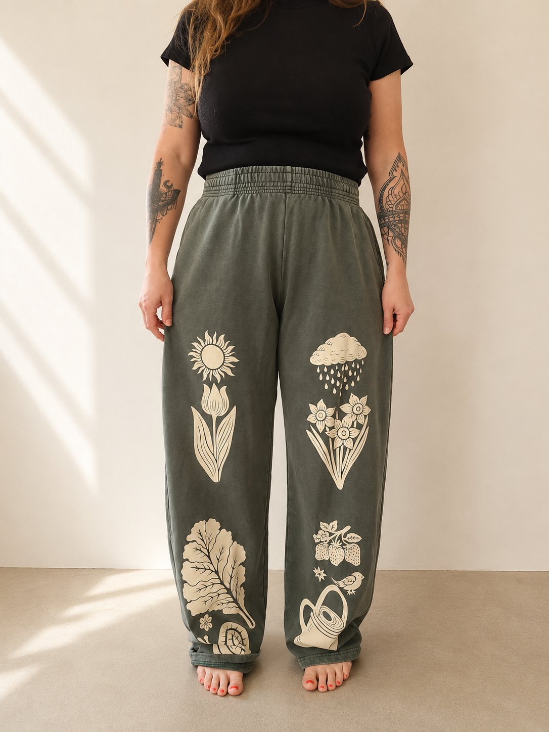 Person wearing olive green pants with floral and nature-themed designs on a neutral background