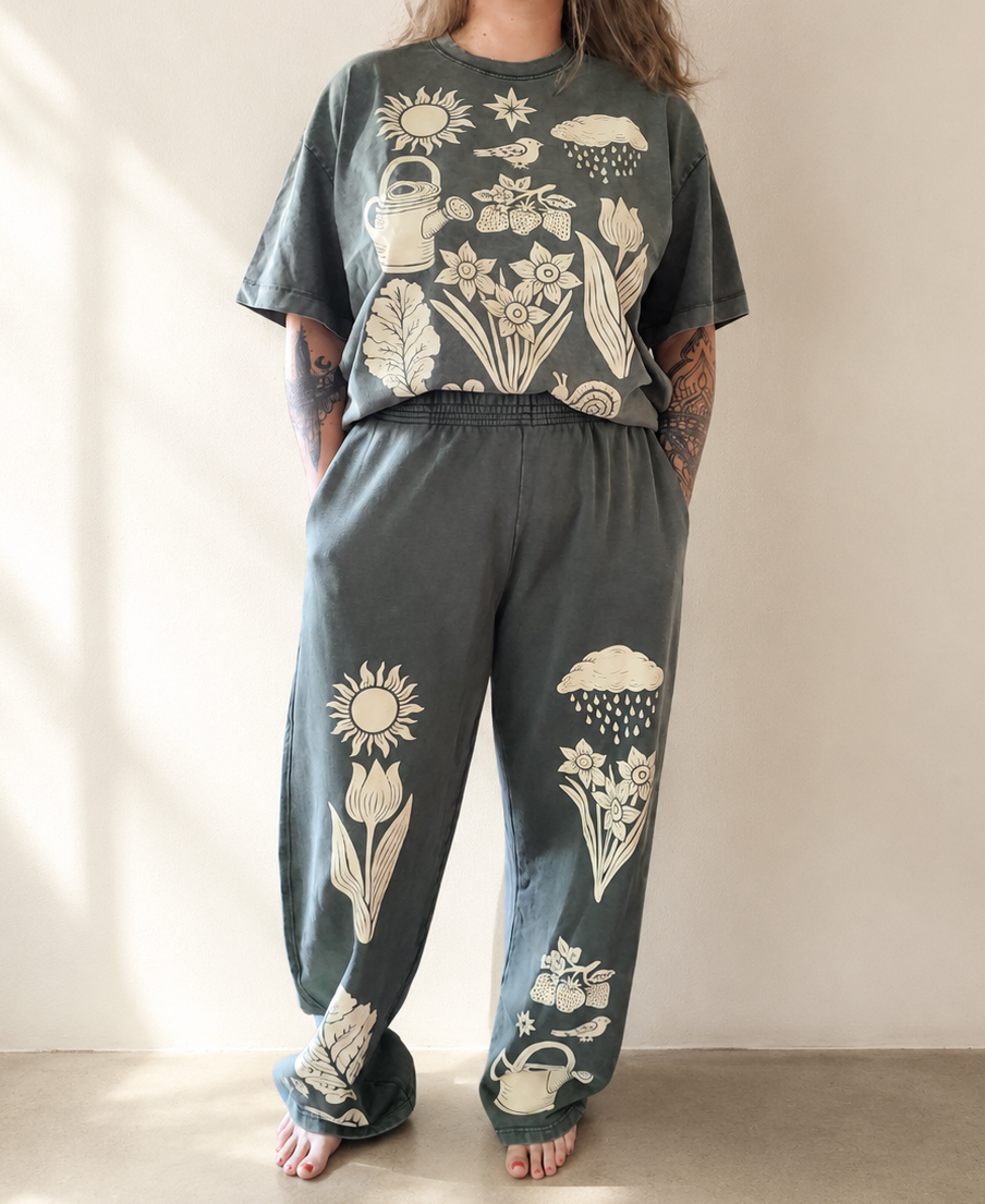 Person wearing a matching set of t-shirt and pants with nature-themed designs in a minimal setting.