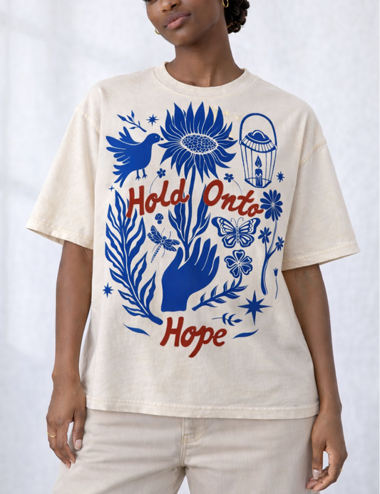 Person wearing a cream t-shirt with blue and red graphic design and text.