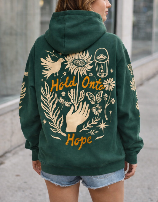 Person wearing a green hoodie with artistic designs and 'Hold Onto Hope' text.