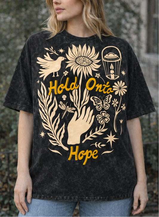 Woman wearing a black t-shirt with artistic designs and text outdoors