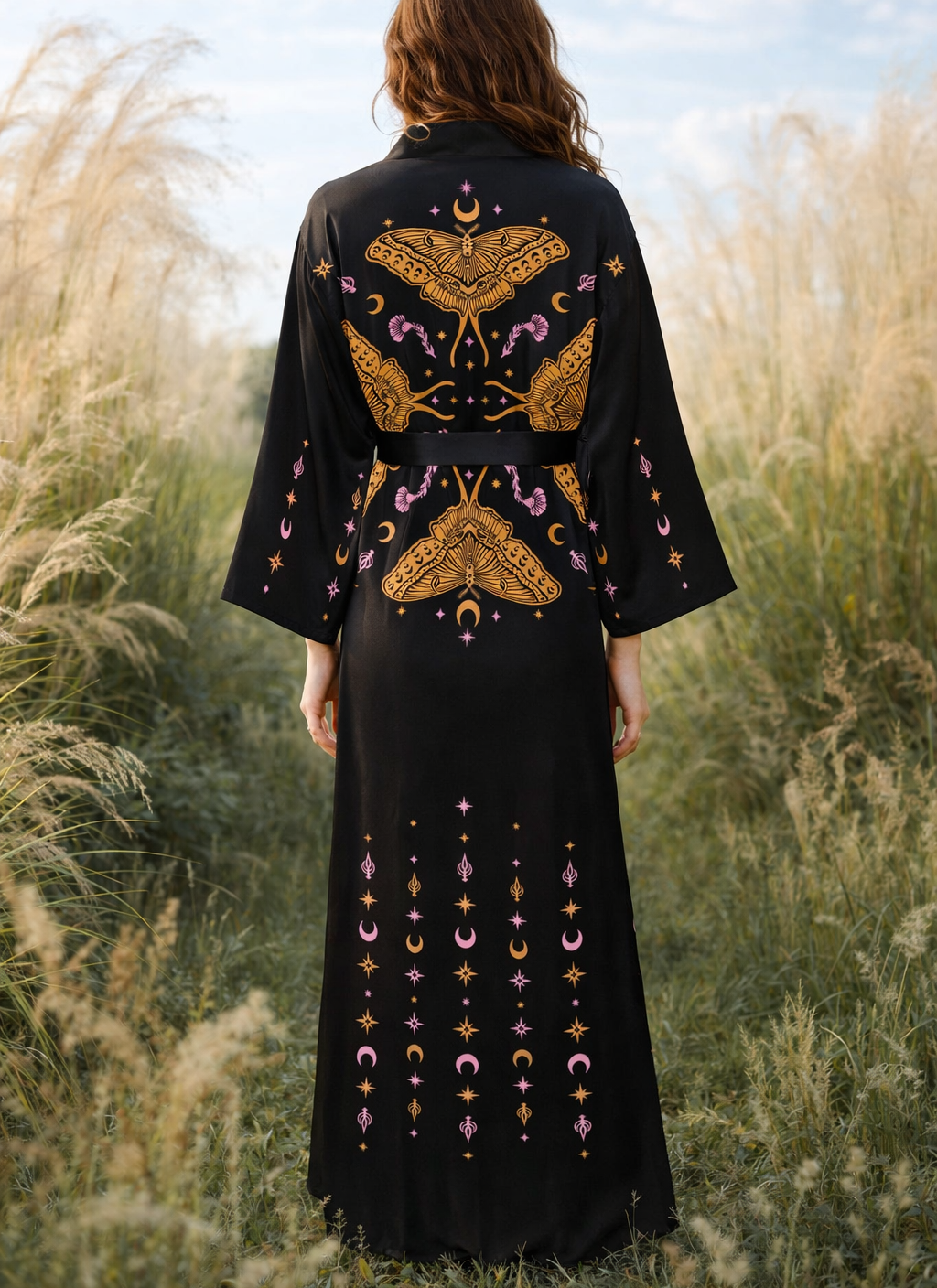 Woman wearing a black witchy moth celestial embroidered kimono robe dress standing in a field