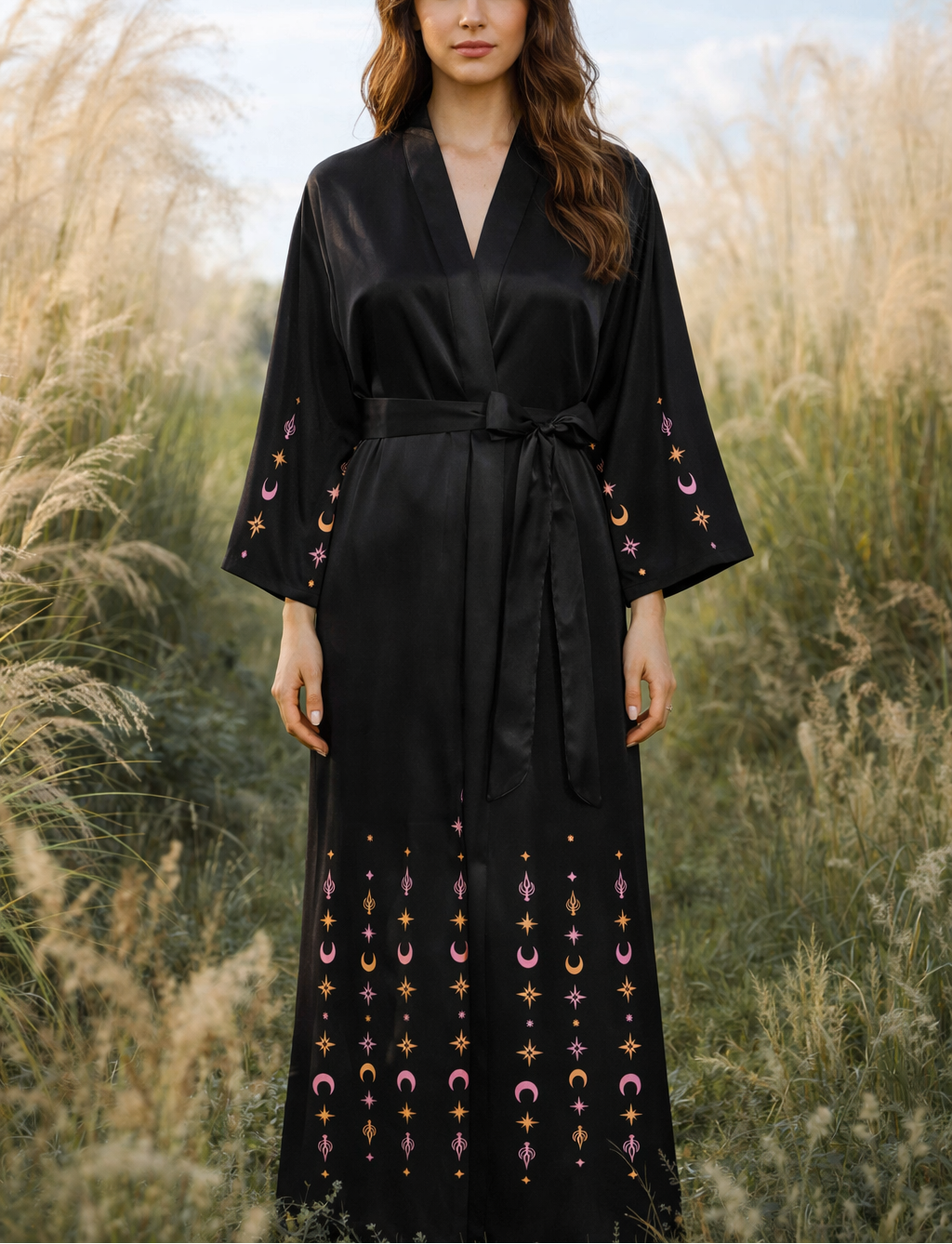 Woman wearing a black and golden moth queen kimono robe dress with celestial patterns in a field. Festival witchy kimono