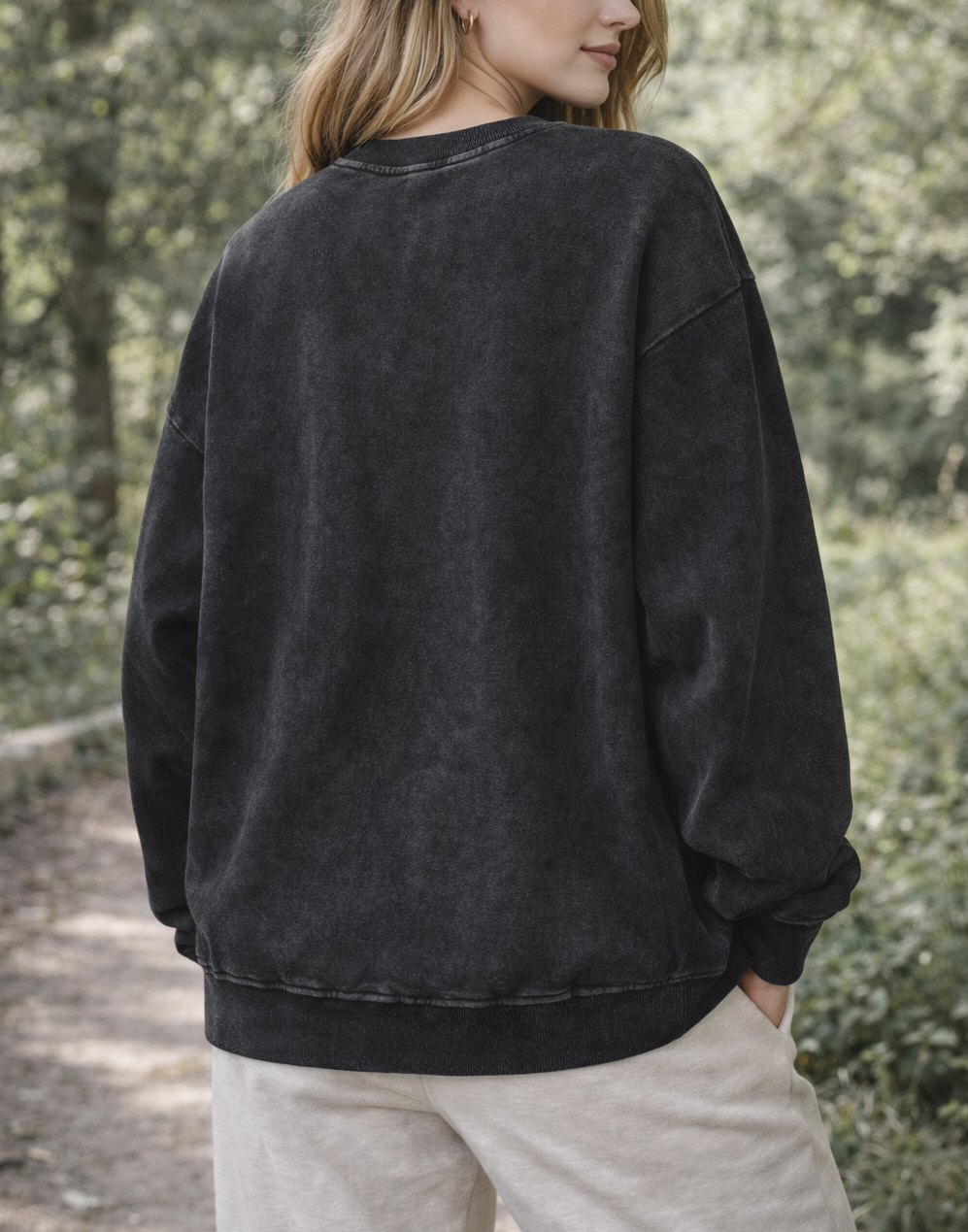 Person wearing a black sweatshirt in a forest setting