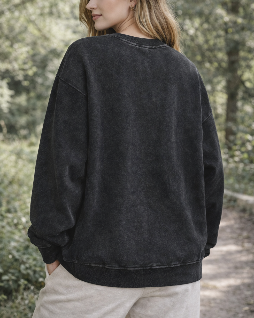 Person wearing a black sweatshirt in a forest setting