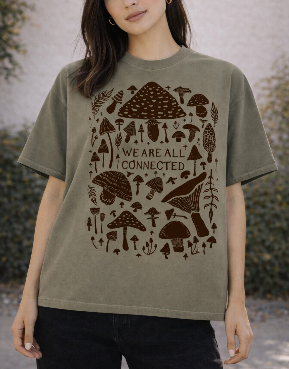 Woman wearing a green t-shirt with brown mushroom design and text outdoors.