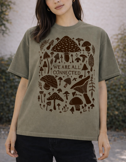 Woman wearing a green t-shirt with brown mushroom design and text outdoors.