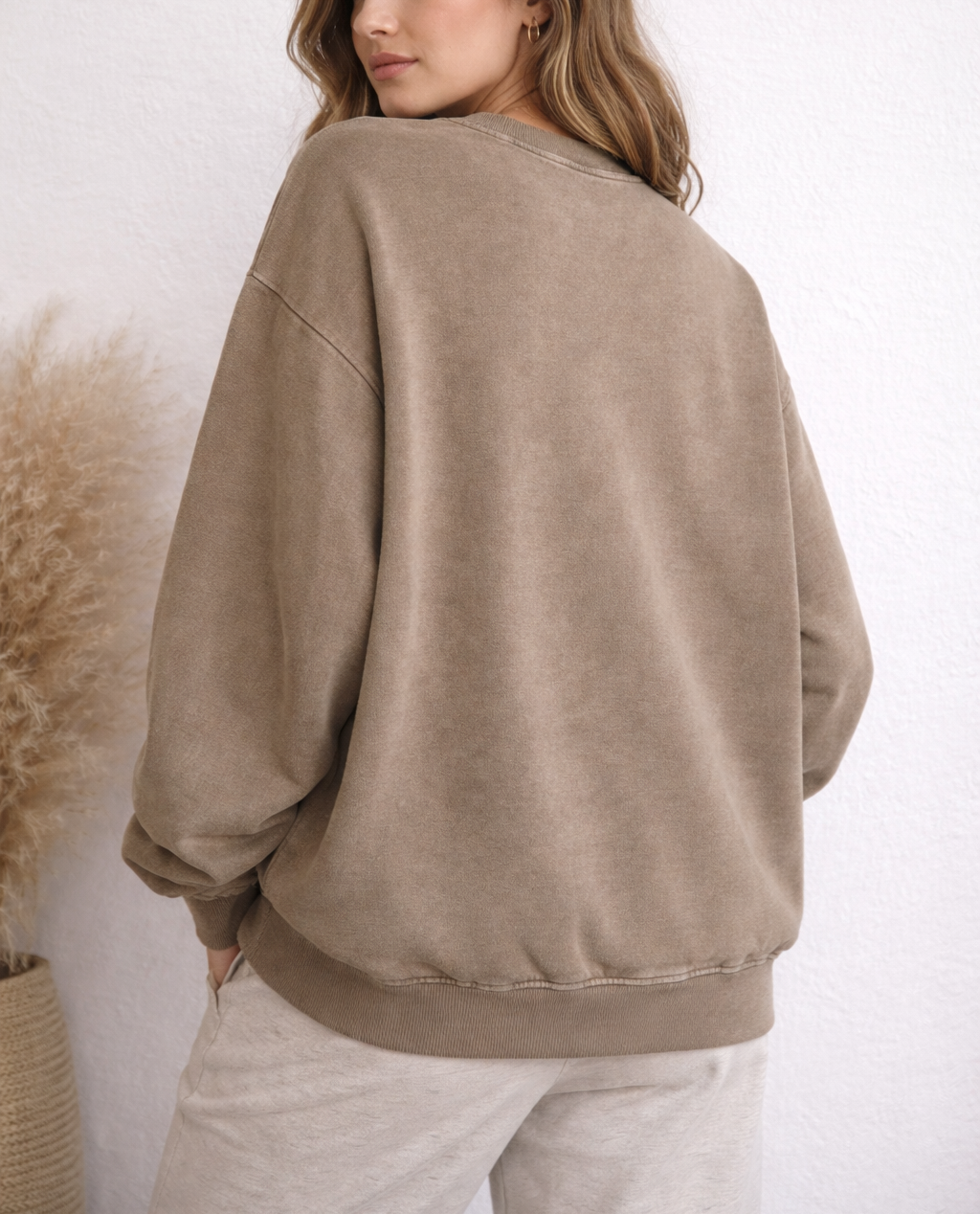 Woman wearing a beige sweatshirt and pants against a white background