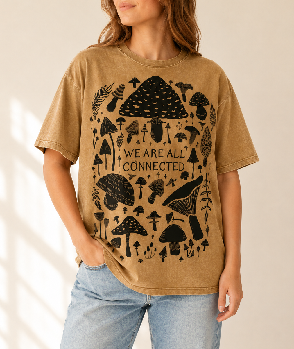 Woman wearing a brown t-shirt with black mushroom design and 'We Are All Connected' text.
