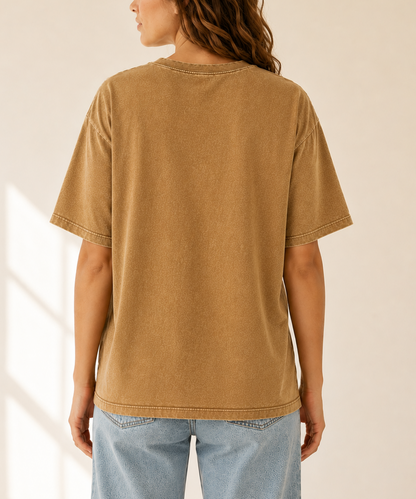 Person wearing a brown t-shirt and light blue jeans against a neutral background