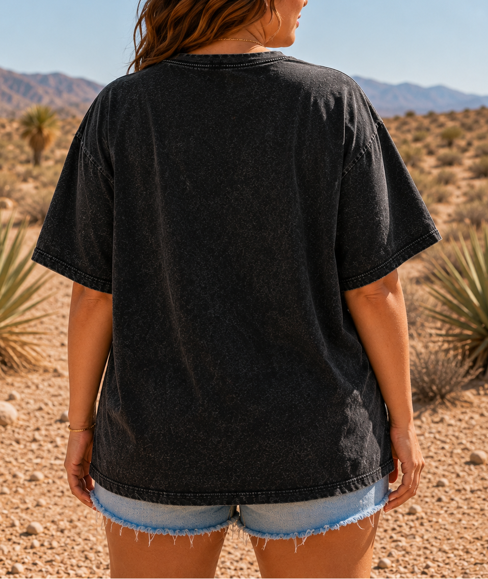 Person wearing a black t-shirt and denim shorts standing in a desert landscape.