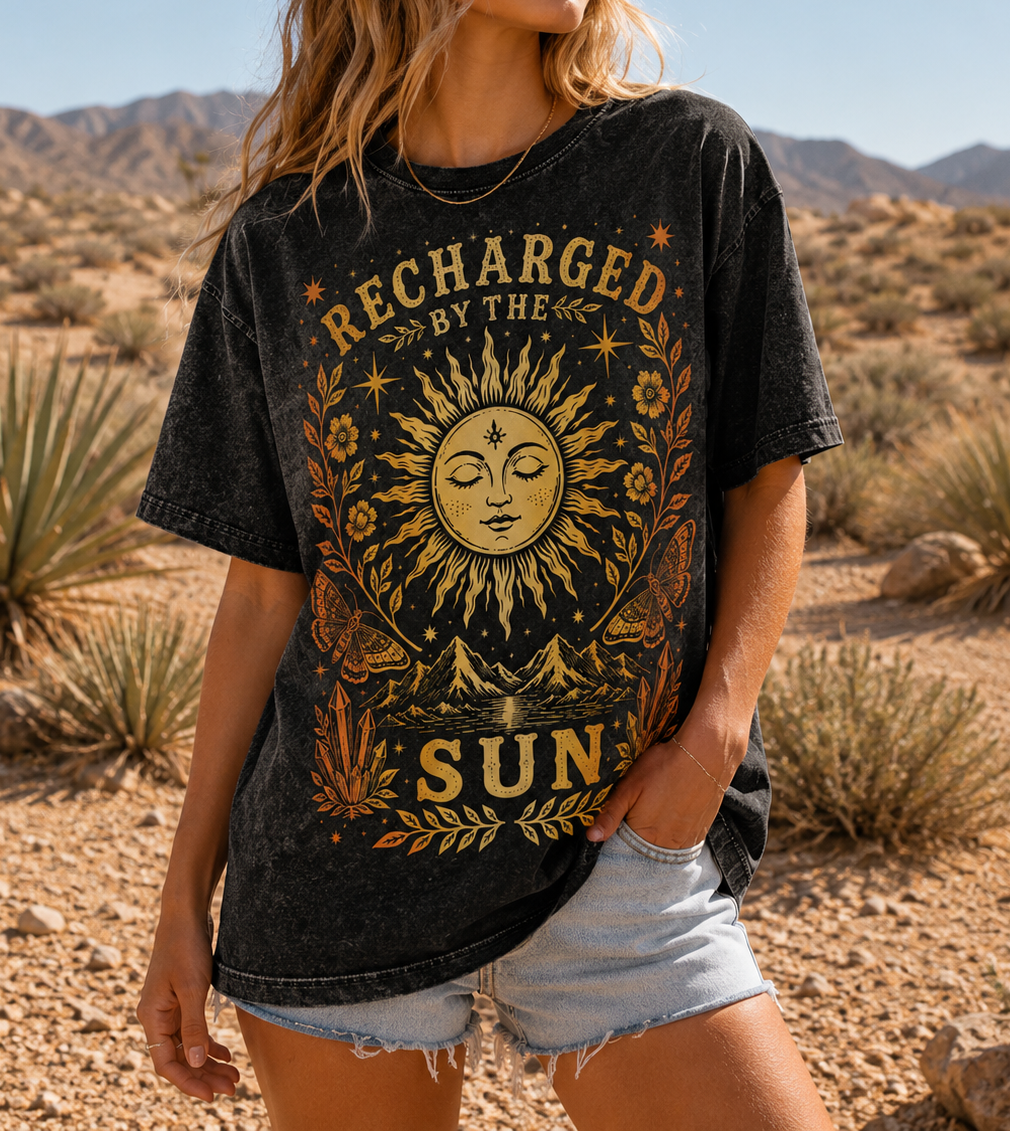 Woman wearing a black t-shirt with sun graphic and 'Recharged by the Sun' text in a desert setting