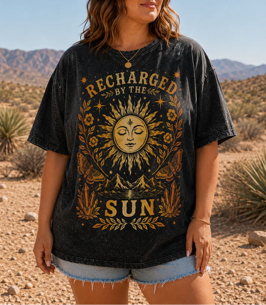 Woman wearing a black t-shirt with sun design and 'Recharged by the Sun' text in a desert setting
