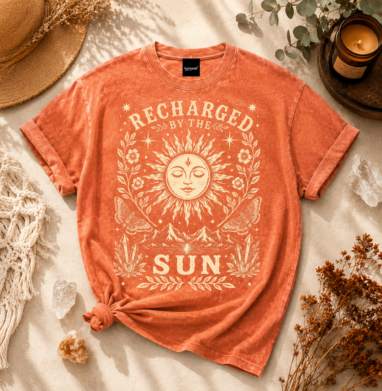 Orange t-shirt with sun graphic and 'Recharged by the Sun' text on a neutral background