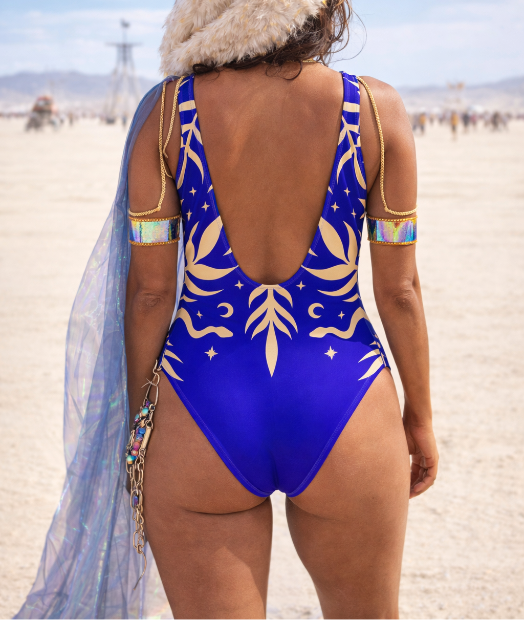 Person wearing a blue slimming snake and plant swimsuit with gold patterns in a desert setting