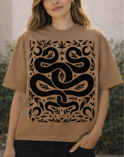 Woman wearing a brown t-shirt with a black snake design outdoors.