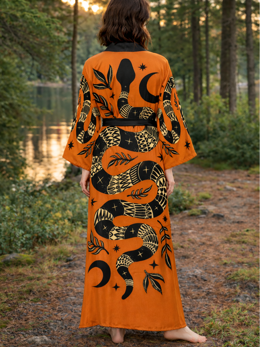 Person wearing an orange dress with black snake design in a forest setting