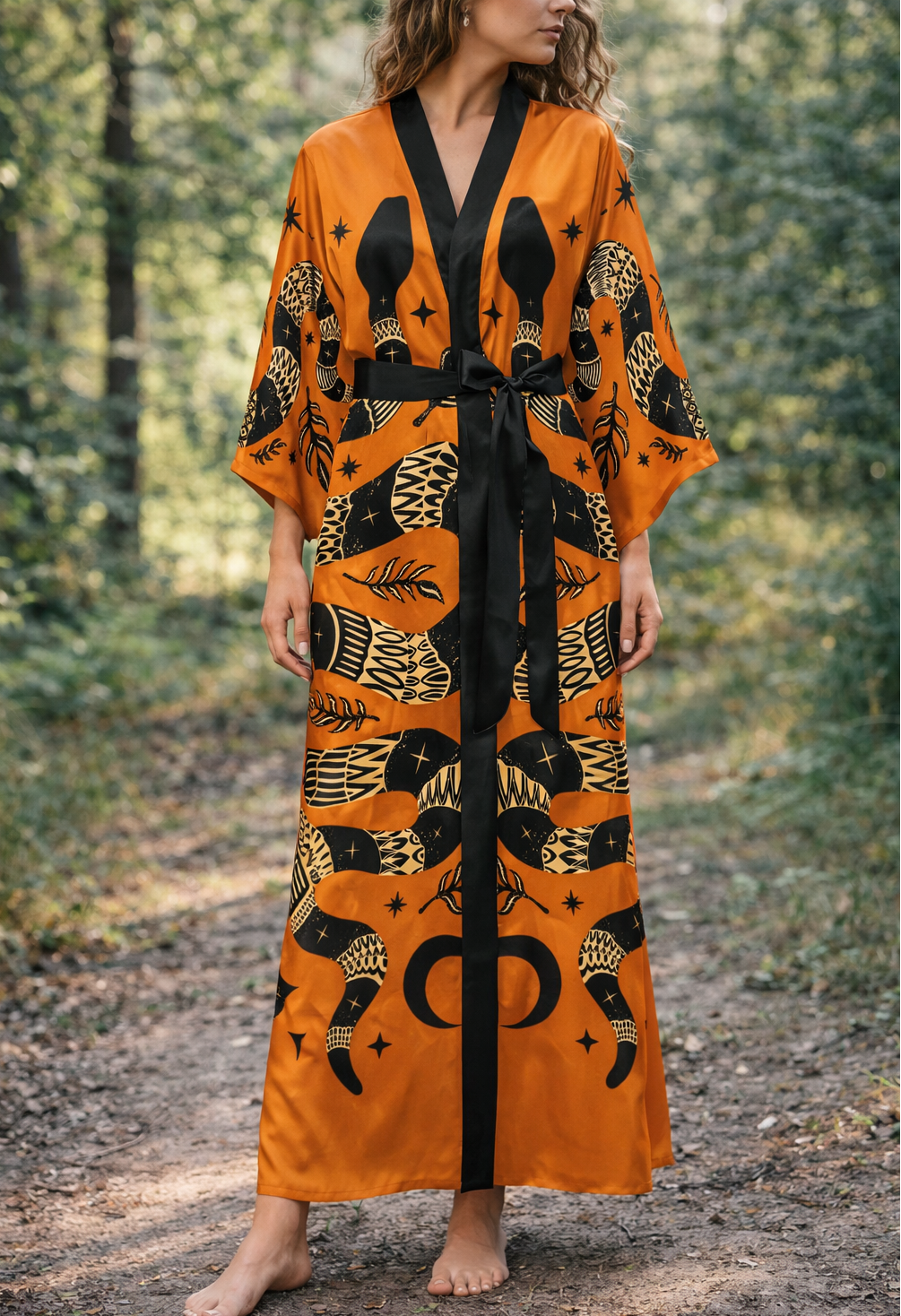 Woman wearing an orange and black snake patterned kimono robe in a forest setting