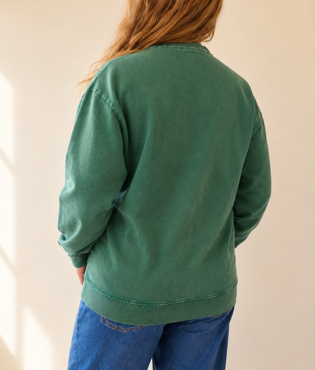 Person wearing a green sweatshirt and blue pants against a plain background