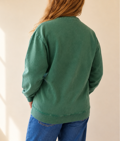 Person wearing a green sweatshirt and blue pants against a plain background