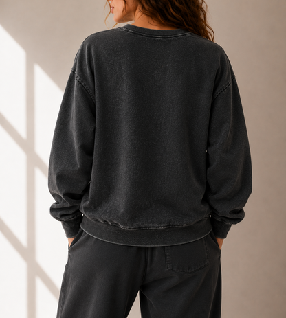 Person wearing a black sweatshirt and pants against a neutral background