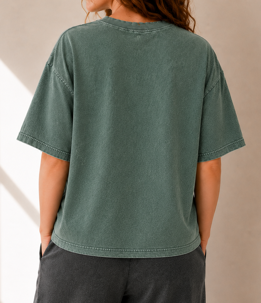 Person wearing a green t-shirt and dark pants against a neutral background