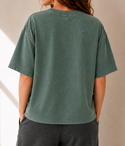 Person wearing a green t-shirt and dark pants against a neutral background