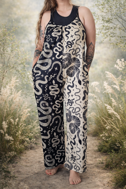 Person wearing a color block black and cream patterned jumpsuit standing in a natural setting with plants and flowers.