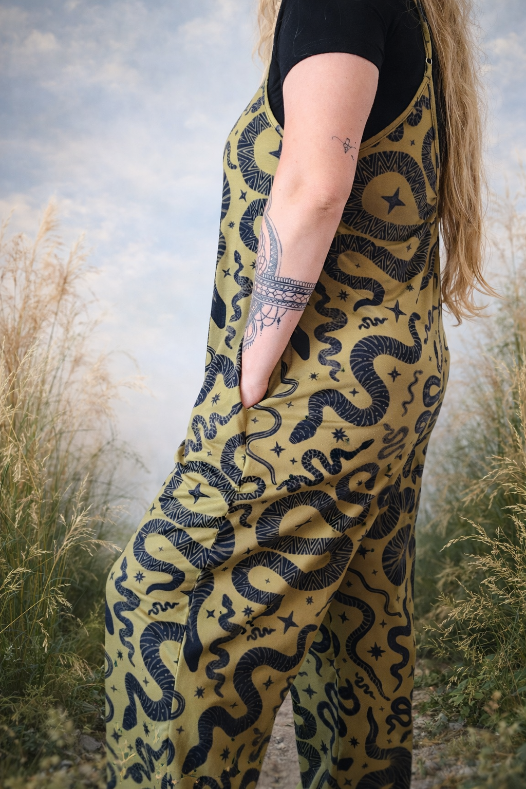 Person wearing a snake patterned jumpsuit with pockets with a snake design in a natural setting