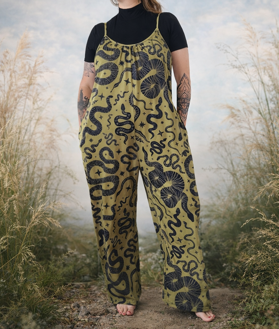 Person wearing a snake patterned jumpsuit standing in a natural setting with tall grass and a cloudy sky.