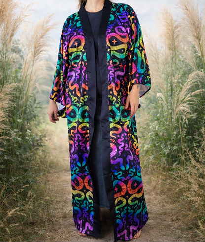 Person wearing a colorful snake patterned kimono robe coat standing in a field of tall grass.